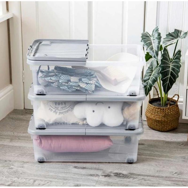 Wheeled underbed storage box sliding out from under a bed on castors